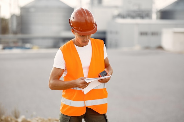 Photo gratuite ingénieur dans un casque debout près de l'usine