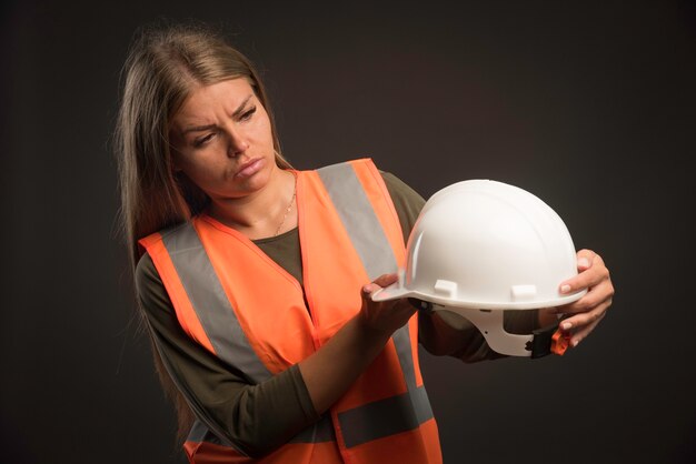 Ingénieur femme tenant un casque blanc et a l'air sérieux.