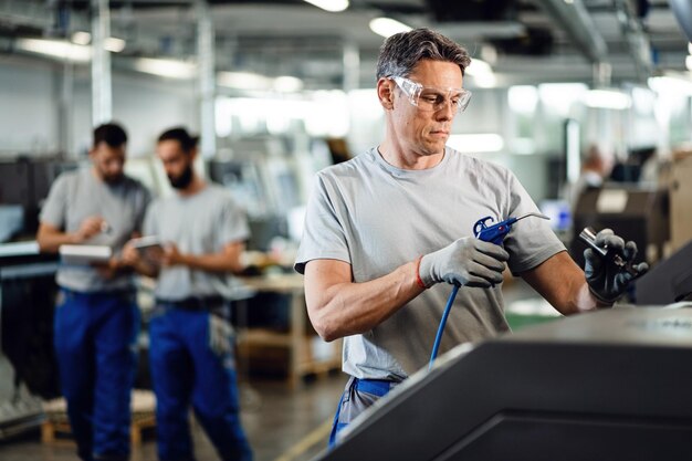 Ingénieur mi-adulte utilisant une machine CNC dans une ligne de production dans une usine