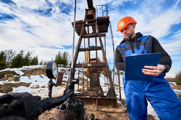 Ingénieur pétrolier inspectant le cric de la pompe dans le champ pétrolifère