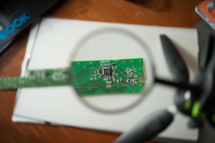 Photo gratuit ingénieur regardant une carte de circuit imprimé à travers une loupe
