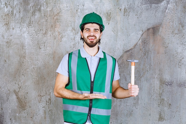 Ingénieur en tenue jaune et casque tenant une hache à manche en bois.