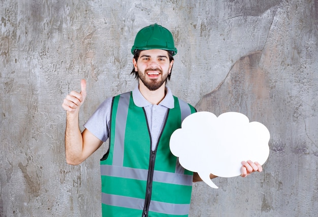 Photo gratuite ingénieur en tenue jaune et casque tenant un tableau d'informations en forme de nuage et profitant de ce projet