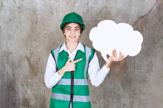 Ingénieur en uniforme vert et casque tenant un panneau d'information en forme de nuage.