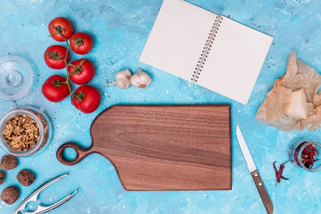 Ingrédient sain et ustensile de cuisine avec journal vierge ouvert sur fond texturé bleu