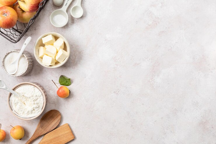 Ingrédients pour une tarte aux pommes sucrée sur un fond clair de pierre