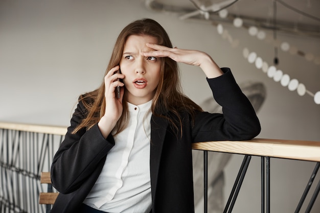 Photo gratuite inquiet jeune femme d'affaires au café parler par téléphone