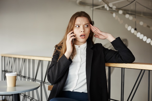 Inquiet jeune femme d'affaires au café parler par téléphone