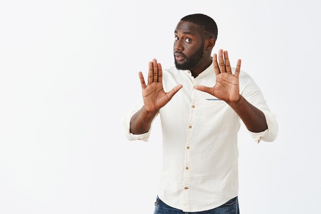 Inquiet jeune mec posant contre le mur blanc