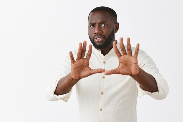 Inquiet jeune mec posant contre le mur blanc