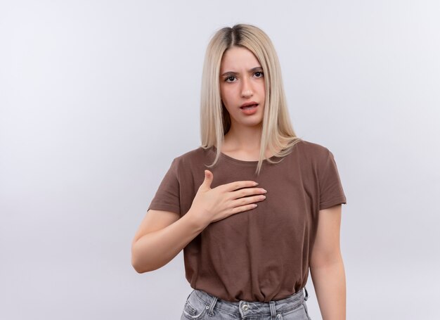 Insatisfait jeune fille blonde avec la main sur la poitrine sur un mur blanc isolé avec copie espace