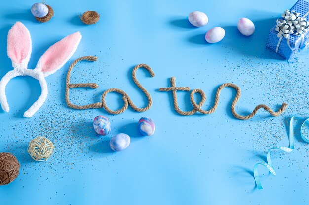 Inscription créative de Pâques sur bleu avec des éléments de décor de Pâques.