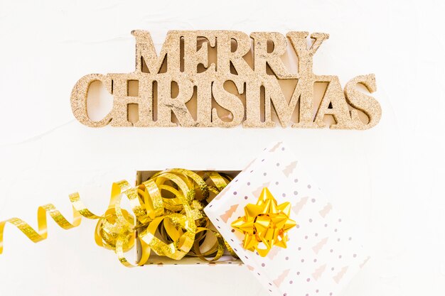 Inscription décorative joyeux Noël près de boîte-cadeau avec ruban