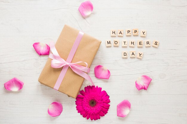 Inscription heureuse fête des mères avec boîte-cadeau et gerbera