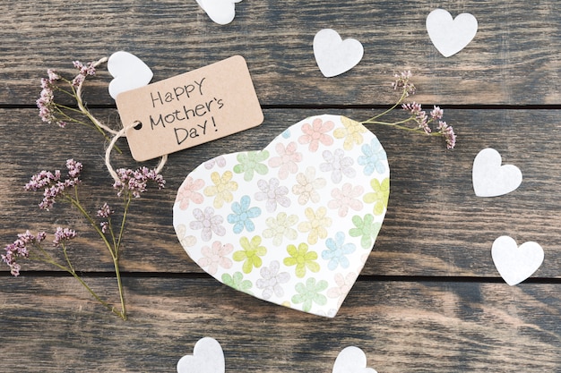 Inscription heureuse fête des mères avec des fleurs un coeurs de papier