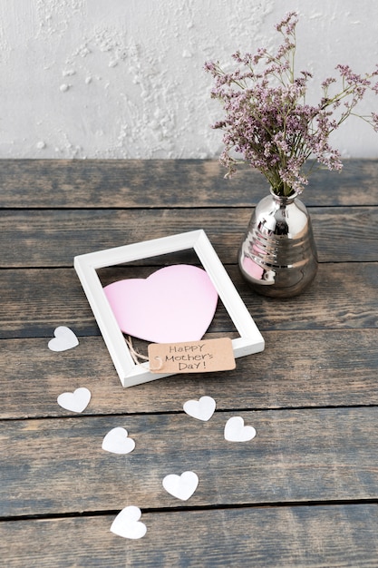 Inscription heureuse fête des mères avec des fleurs dans un vase et un cadre