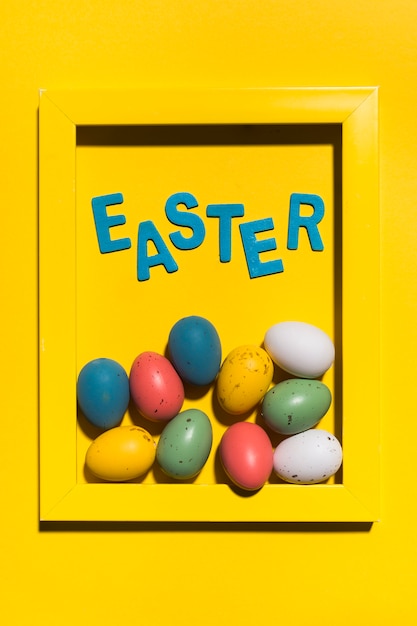 Inscription de Pâques dans le cadre avec des oeufs colorés sur la table