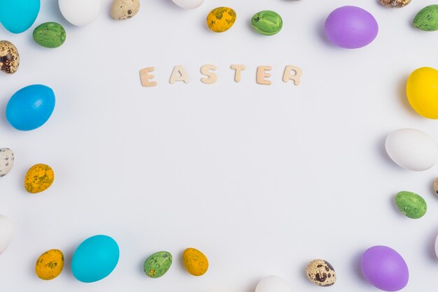 Inscription de Pâques avec des oeufs colorés sur la table