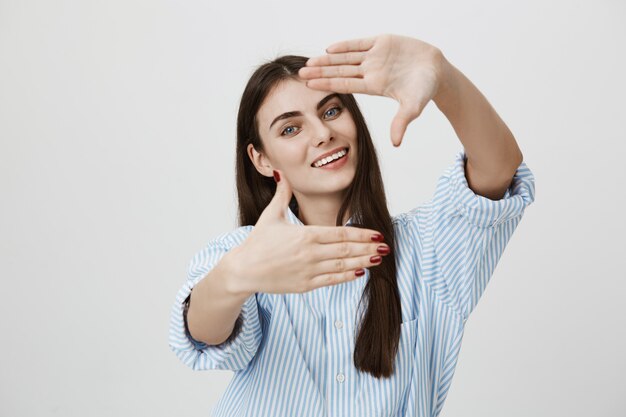 Insouciante souriante jolie femme faire un geste de cadre