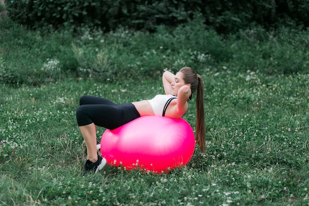 Instructeur de conditionnement physique à l&#39;aide de yoga exercice ballon extérieur haute herbe verte dans le parc