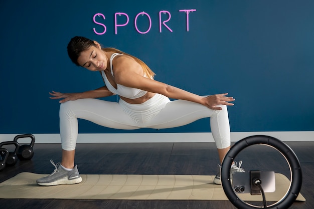 Instructeur de fitness féminin travaillant à la maison devant le ring light
