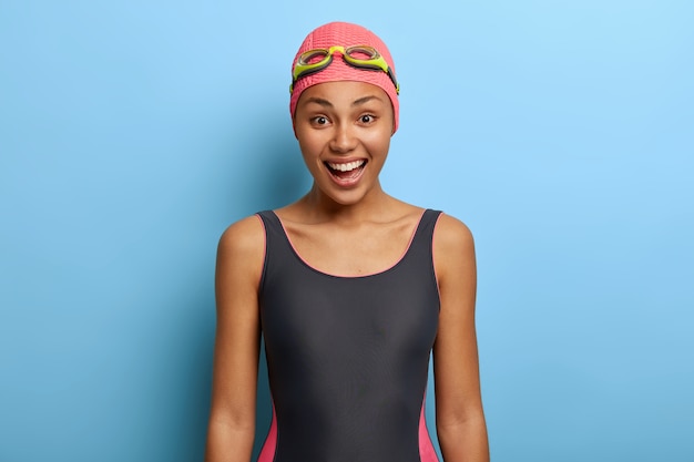 Instructeur de natation noir positif habillé en maillot de bain, bonnet de bain et lunettes