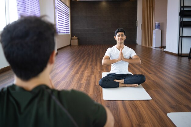 Instructeur de yoga méditant avec un étudiant en salle de sport