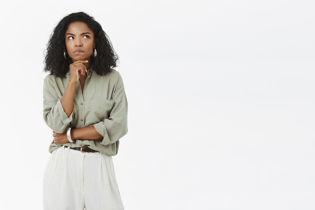 Intense, intelligente et réfléchie, belle femme en t-shirt gris et pantalon fronçant les sourcils regardant le coin supérieur droit tout en pensant