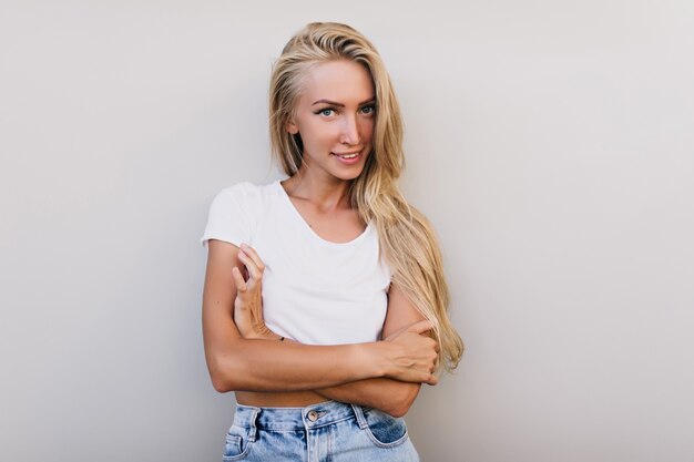 Intéressé jeune femme à la peau bronzée qui pose en studio. Plan intérieur d'une femme caucasienne heureuse en débardeur d'été.