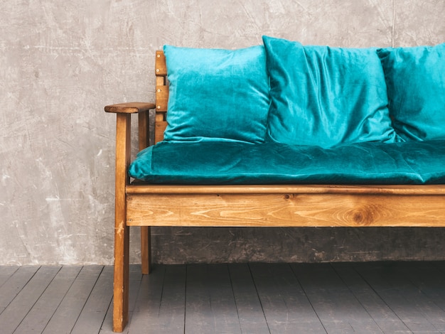 Intérieur du mur gris avec un élégant canapé moderne rembourré bleu et bois, lampes suspendues