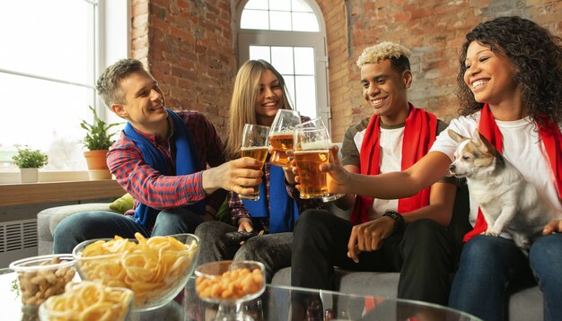 À l'intérieur. Des gens excités qui regardent un match de sport, un championnat à la maison. Groupe multiethnique d'amis, fans encourageant l'équipe sportive préférée