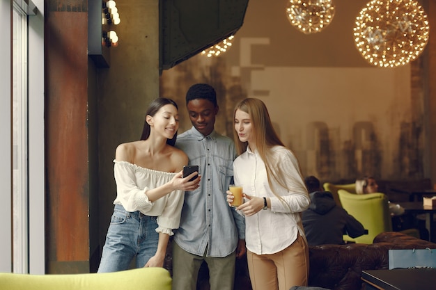 Internationals personnes debout dans un café avec téléphone portable