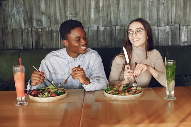 Photo gratuite des internationaux assis à table avec des salades et des cocktails