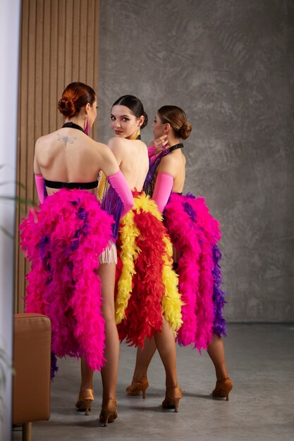 Interprètes féminins de cabaret posant dans les coulisses en costumes de plumes