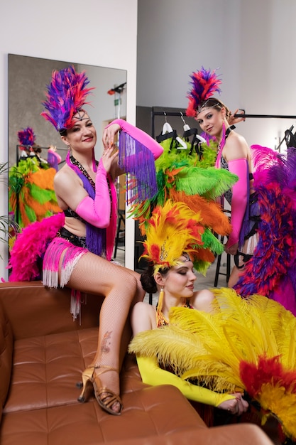 Interprètes féminins de cabaret posant dans les coulisses en costumes de plumes