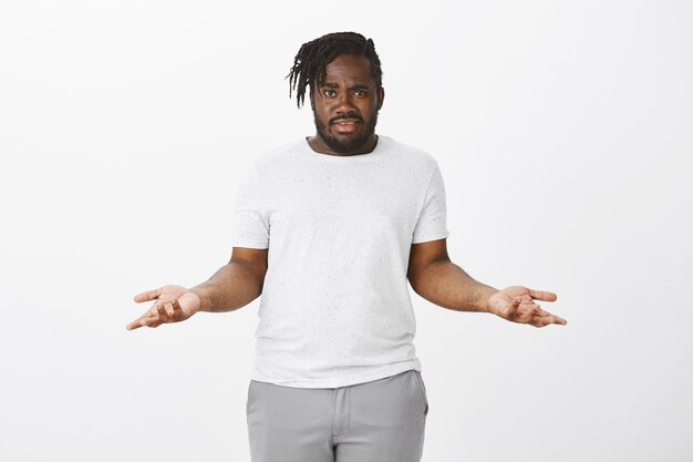 interrogé mec avec des tresses posant contre le mur blanc