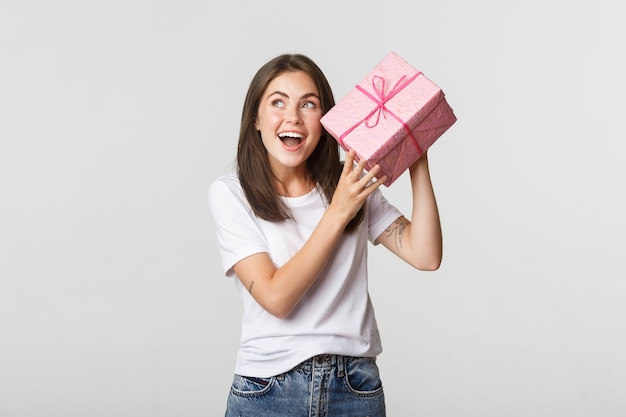 Intrigué joyeux anniversaire fille secouant la boîte-cadeau pour savoir ce qu'il y a à l'intérieur.