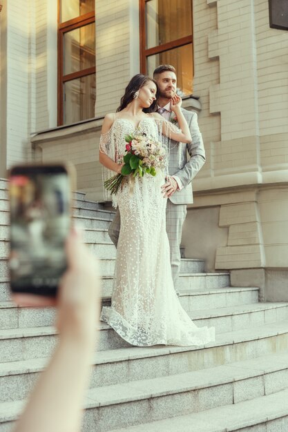 Invité faisant photo de jeune couple romantique caucasien célébrant le mariage en ville.