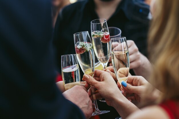 Les invités clangent des verres de champagne avec de délicieuses fraises