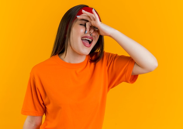 Irritée jeune femme sportive portant un bandeau et des bracelets tenant le nez avec les yeux fermés