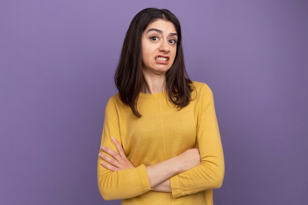 Irritée jeune jolie fille caucasienne debout avec une posture fermée isolée sur un mur violet avec espace de copie