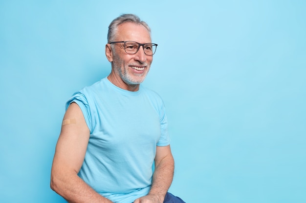 J'ai reçu le vaccin Covid 19. Un vieil homme barbu souriant montre l'épaule avec un pansement après la vaccination