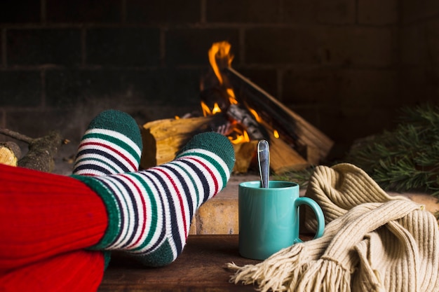 Jambes de culture et des boissons près de cheminée et écharpe