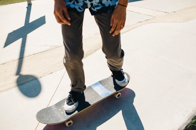 Les jambes du mec moderne pendant la planche à roulettes