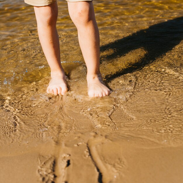 Jambes de l&#39;enfant dans l&#39;eau sur la plage