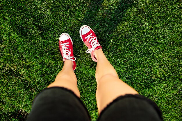 Jambes de femme debout sur l'herbe dans le parc