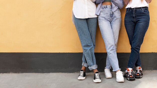 Jambes de femmes devant un mur jaune avec espace copie