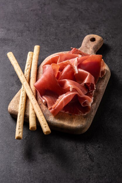 Jambon serrano espagnol avec gressin sur fond noir