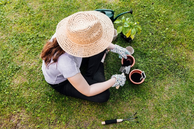 Photo gratuite jardinier à angle élevé assis et plantant