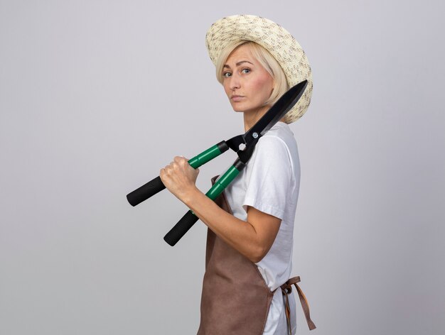 Jardinier blonde d'âge moyen confiant femme en uniforme portant un chapeau